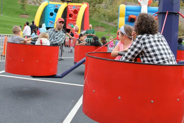 Families enjoying tub carnival rides at an outdoor festival