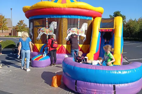 Kids playing on a carousel-themed inflatable bounce house