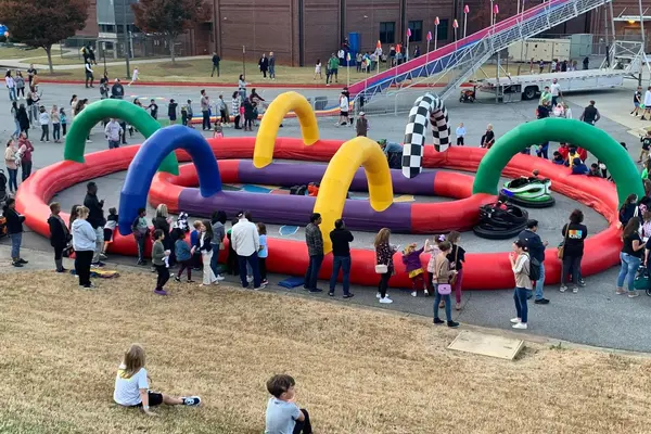 Inflatable go-kart race track with kids at an outdoor festival
