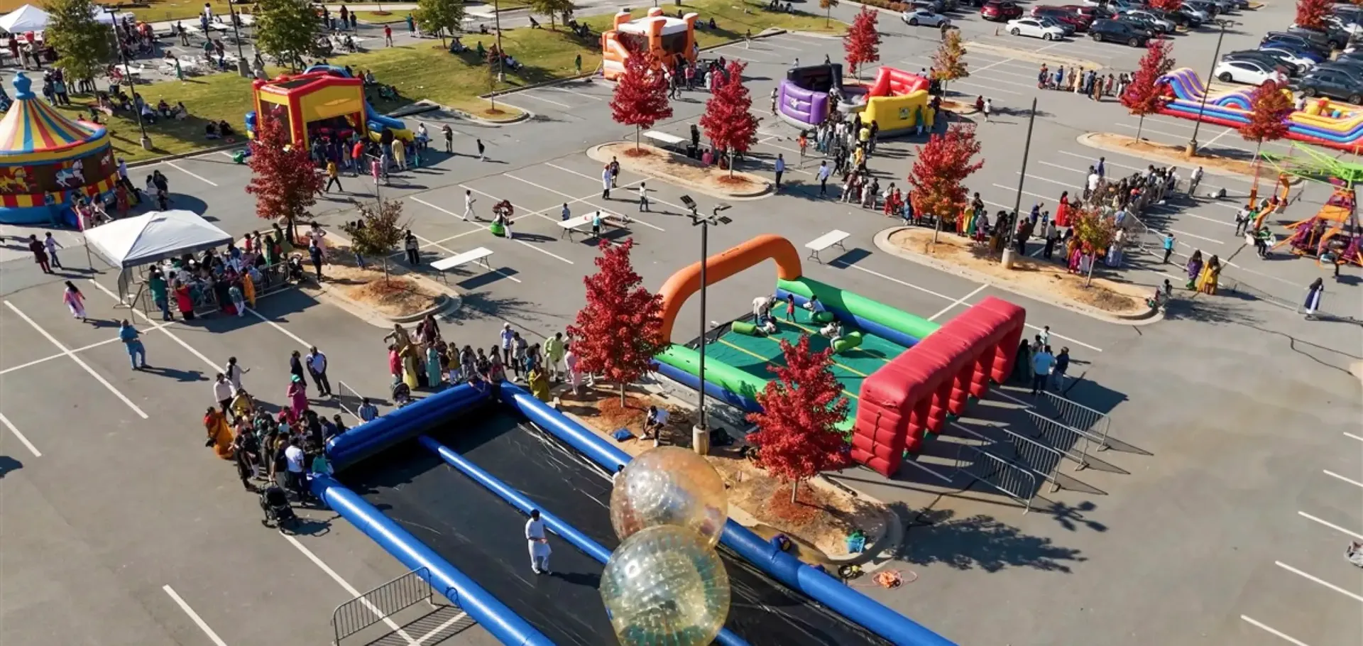 Aerial view of a large outdoor event with inflatables, carnival rides, and crowds in North Georgia