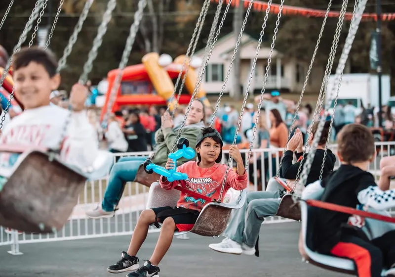 Children enjoying a giant swing carnival ride at a community event